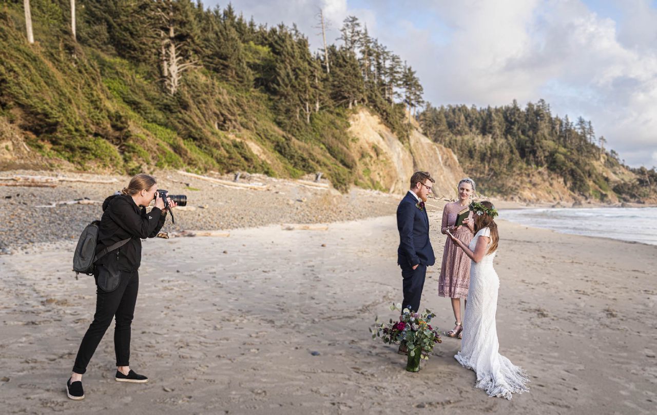 A female wedding photographer taking a picture of a wedding ceremony in the Pacific Northwest