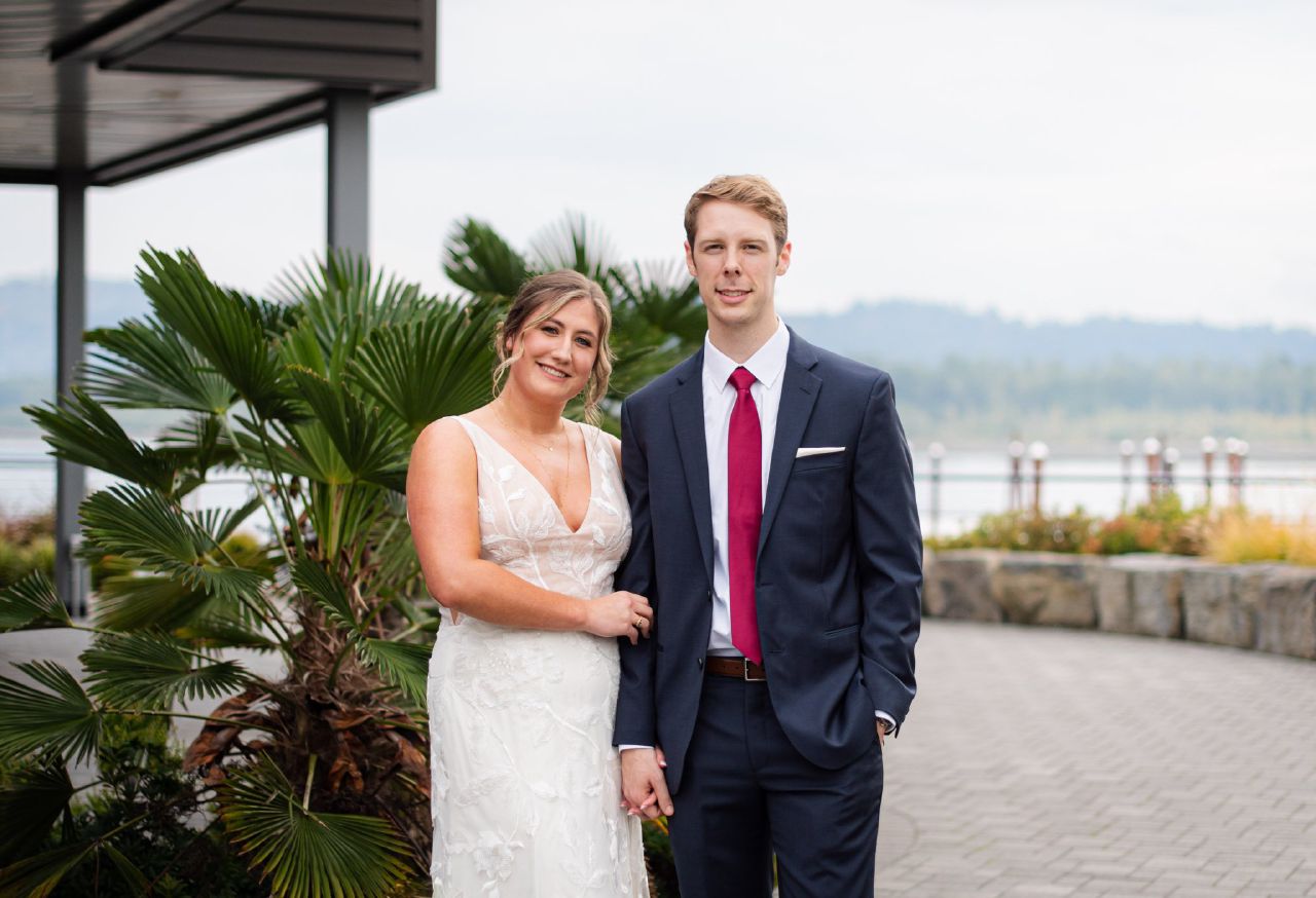 A wedding portrait of a bride and groom outside with the Columbia River in the background