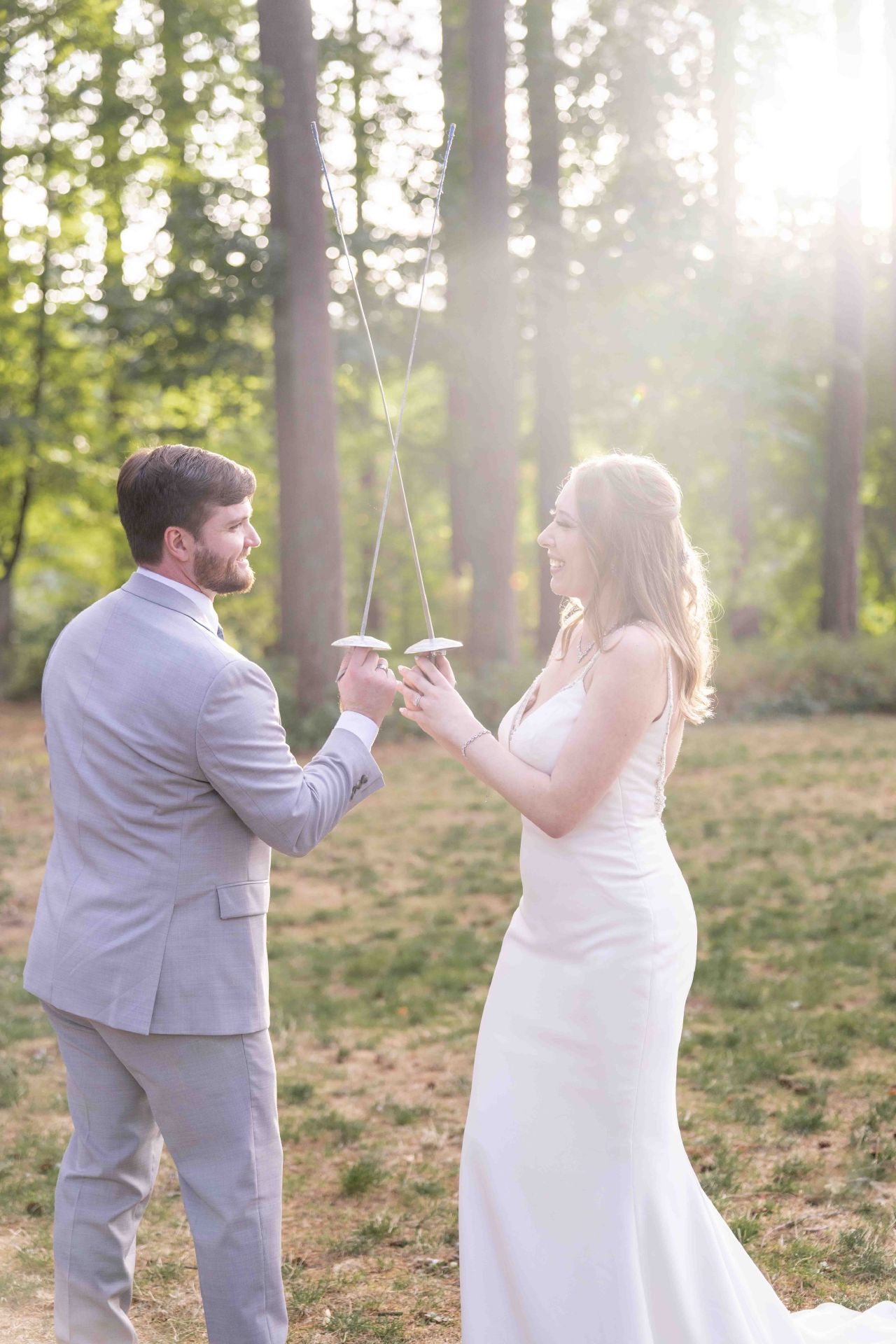Bride and groom cross fencing swords under golden forest light at Lacamas Lake Park wedding in Camas, WA.