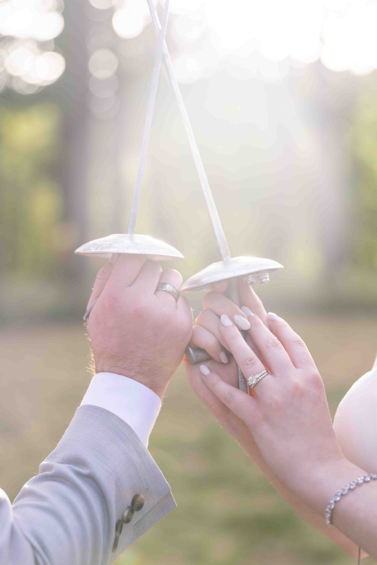 Close-up of wedding rings and crossed fencing foils during romantic Lacamas Lake Park ceremony.